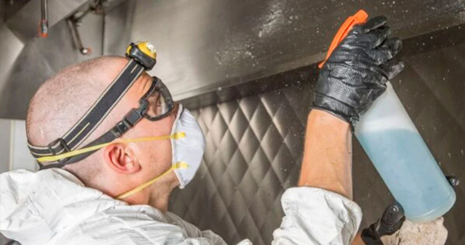 Profissional utilizando luvas de proteção para mostrar como limpar coifa industrial em cozinha de restaurante em Salvador