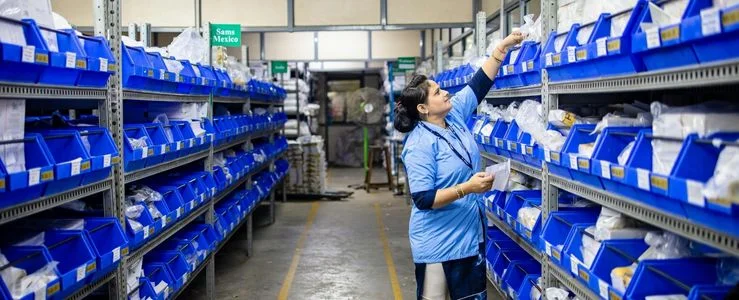 Funcionaaria conferindo a lista de materiais de limpeza para empresas em almoxarifado organizado.